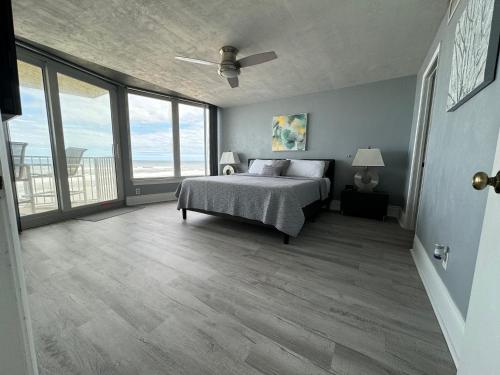 Schlafzimmer mit einem Bett und großen Fenstern in der Unterkunft DIRECT OCEANFRONT NO-DRIVE BEACH CONDO in Daytona Beach