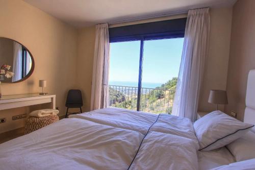 een slaapkamer met een bed en een groot raam bij Los Monteros Penthouse with Panoramic Sea View in Marbella