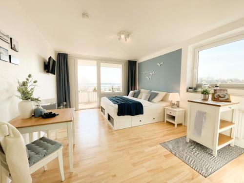 een slaapkamer met een bed, een bureau en een raam bij Ferienwohnung mit Meerblick - Kiek ut in Eckernförde