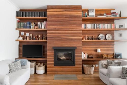 a living room with a fireplace and wooden wall at Family beach house, sea view, pool, Colares near Sintra in Colares