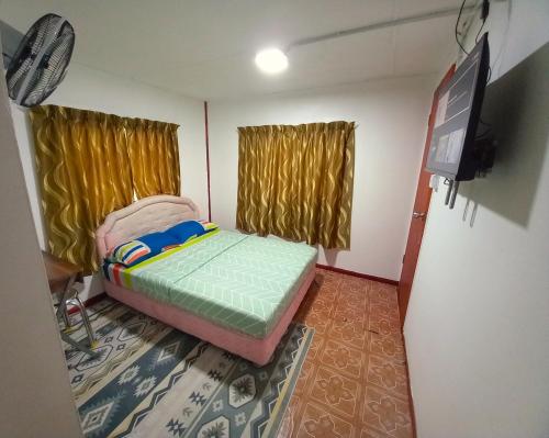 a small room with a bed and a flat screen tv at Soboroong Farmer's Cottage in Kampong Kundassan