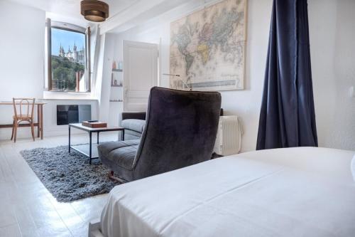 a bedroom with a bed and a chair and a table at 50m² cosy près place Bellecour & vue s/ basilique in Lyon