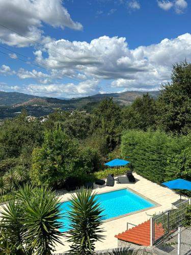 a swimming pool with chairs and umbrellas in a yard at Fontainha House & SPA in Caldelas