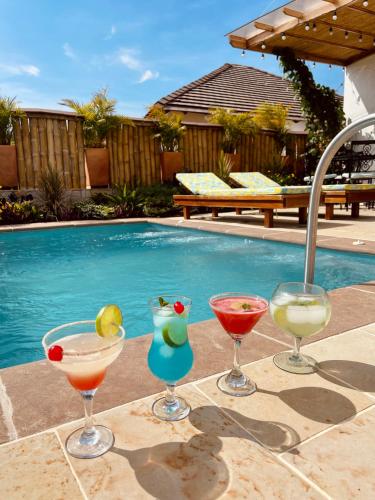 three cocktails sitting on a table next to a swimming pool at Hotel Campestre Palmas del Zamorano in San Gil