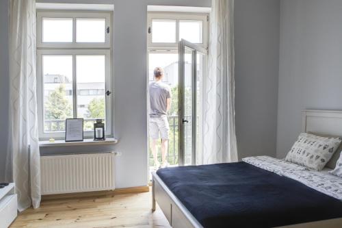 a man looking out the window of a bedroom at Homewell Apartments Pod Szczerbatym in Poznań