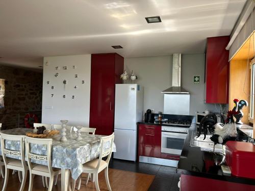 a kitchen with red cabinets and a table with chairs at Fontainha House & SPA in Caldelas