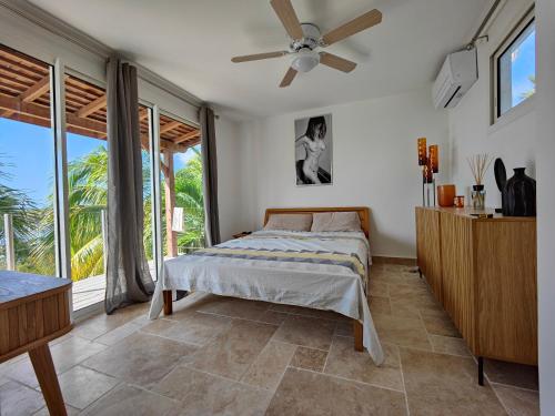 1 dormitorio con 1 cama y ventilador de techo en Villa Nadia - Prestige et Confort Absolu avec Vue Imprenable sur la Mer, en Le Diamant
