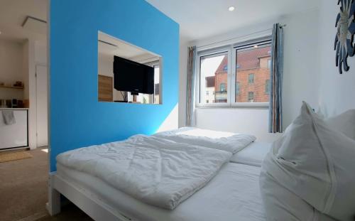 1 dormitorio con cama blanca y pared azul en Urlaub am Rosengarten en Güstrow