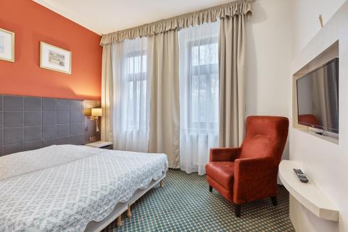 a hotel room with a bed and a chair at Excellent apartments in Spa City Center 5 min walk from the Colonnade in Karlovy Vary