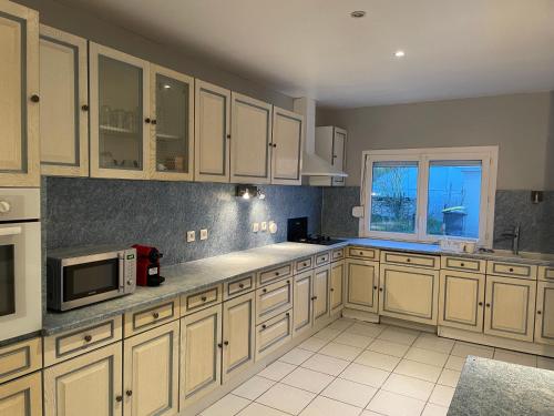 une cuisine avec des armoires blanches et un micro-ondes dans l'établissement Bienvenu dans au Karish, Proche château Chambord et Blois, à Saint-Laurent-Nouan