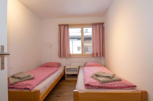 2 Betten in einem kleinen Zimmer mit Fenster in der Unterkunft Ferienwohnung Titschermatte in Adelboden