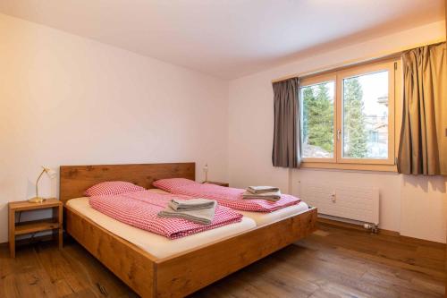 um quarto com uma cama com lençóis cor-de-rosa e uma janela em Ferienwohnung Titschermatte em Adelboden