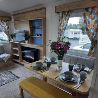 un salon avec une table et une cheminée dans l'établissement Emi's Caravan at Seton Sands Holiday Village, à Port Seton
