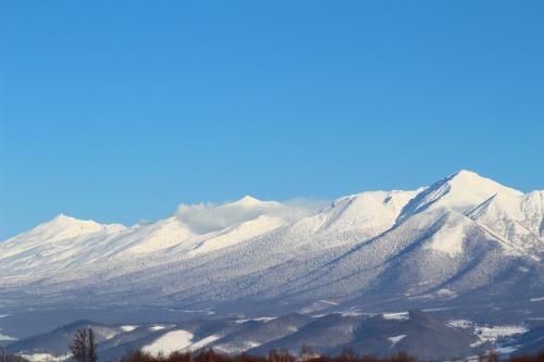 a mountain range with snow covered mountains at ふらの田園コテージヌプリ in Nakafurano