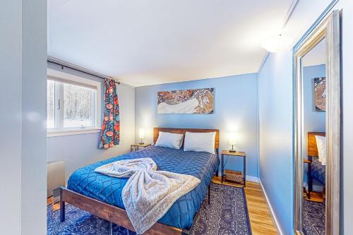 a bedroom with a blue bed and a mirror at Sugarbush Ski Getaway - Lower in Warren