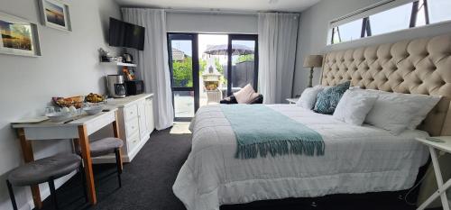 a bedroom with a large bed with a desk and a kitchen at Sunkist B & B in Papamoa