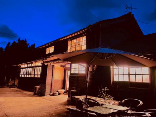 un edificio con una mesa y una sombrilla delante de él en 島宿糸 en Iki