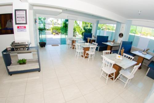 an empty restaurant with tables and chairs and windows at Pousada Dom Marujo in Penha