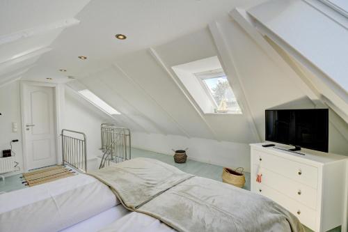 a attic bedroom with a bed and a tv at fewo1846 - Duenengras - elegante Maisonettewohnung mit 3 Schlafzimmern und Balkon in Schausende