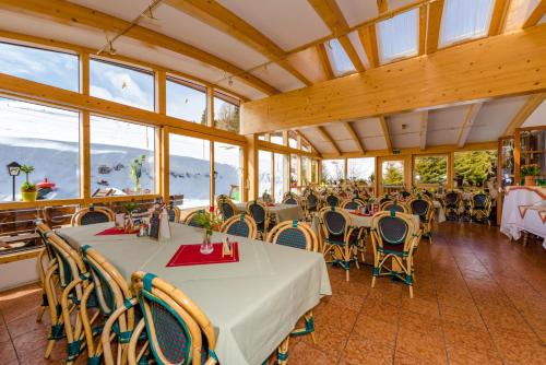 un comedor con mesas, sillas y ventanas en Almidylle Sabathy, en Obdach