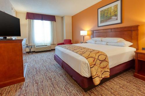a hotel room with a bed and a flat screen tv at Drury Inn & Suites Indianapolis Northeast in Indianapolis