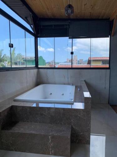 eine große Badewanne in einem Zimmer mit Fenstern in der Unterkunft Loft com Hidro no centro in Balneário Camboriú