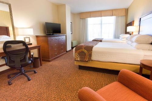 テンピにあるDrury Inn & Suites Phoenix Tempeのベッド、デスク、椅子が備わるホテルルームです。
