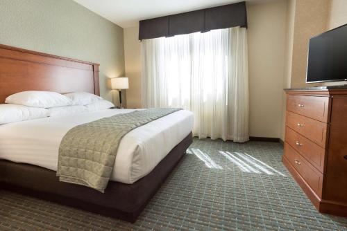 a hotel room with a bed and a flat screen tv at Drury Inn & Suites Burlington in Burlington