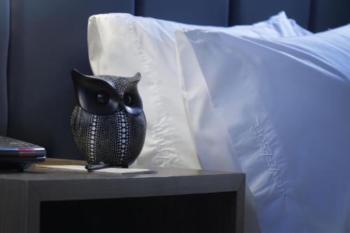 a black owl sitting on a table next to a bed at voco Saltillo Suites by IHG in Saltillo