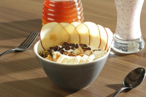 a bowl of fruit with apples and chocolate on a table at voco Saltillo Suites by IHG in Saltillo