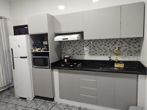 eine Küche mit weißen Schränken und einem weißen Kühlschrank in der Unterkunft Apartamentos aconchegantes no centro da cidade in Cacoal