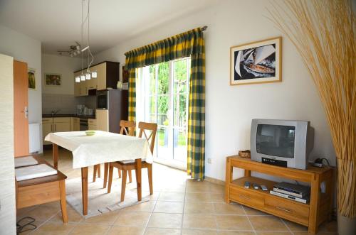 eine Küche und ein Esszimmer mit einem Tisch und einem TV in der Unterkunft Ferienhaus Lütt Eiland in Polchow