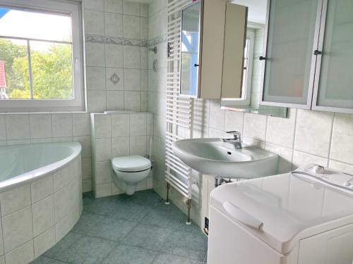 La salle de bains est pourvue d'un lavabo, d'une baignoire et de toilettes. dans l'établissement Ferienwohnung Osterholz, à Baabe
