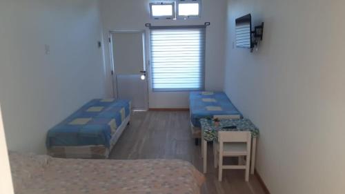 a room with two beds and a table and a door at ABBA Departamento Turístico 3 in Trevelin