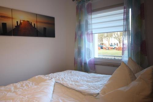 a bed sitting in a bedroom with a window at Kurparkcarree - Ferienwohnung Meeresbrise in Juliusruh
