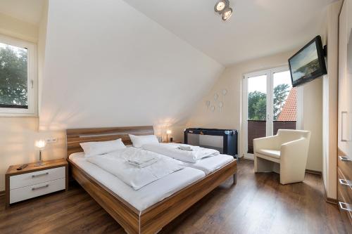 1 dormitorio con 1 cama, TV y silla en Ferienhaus Leuchtturmblick, en Glowe