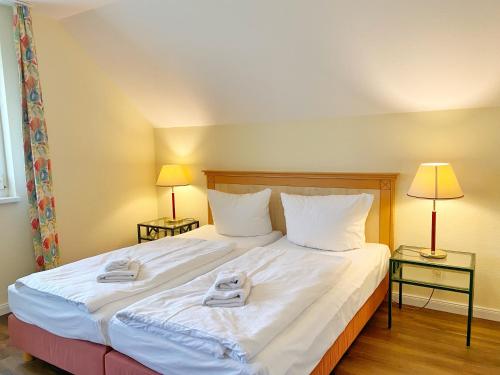sypialnia z dużym białym łóżkiem z 2 lampami w obiekcie Neddesitz Ferienwohnung Kreideblick w mieście Neddesitz
