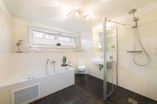 a bathroom with a tub and a sink and a shower at Dünenresort Binz - Ferienwohnung 4.1.6 in Binz