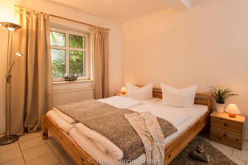 a bedroom with a bed with white pillows and a window at Ferienhaus am Ufer - Ferienwohnung Strandsand in Sassnitz