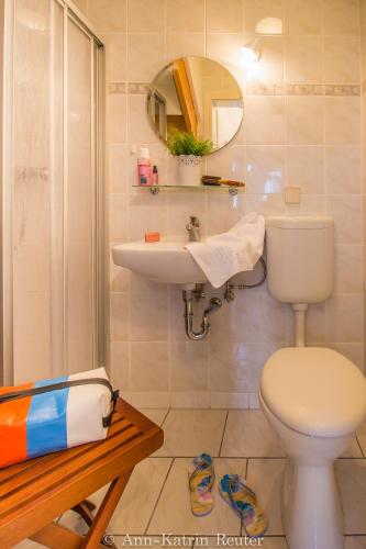 a bathroom with a toilet and a sink and a mirror at Ferienhaus am Ufer - Ferienwohnung Strandsand in Sassnitz