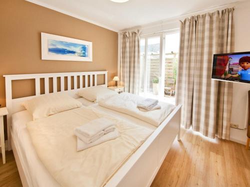 a bedroom with a large white bed with a flat screen tv at _ARW3_ _ Ferienwohnung Kossmann in Niendorf