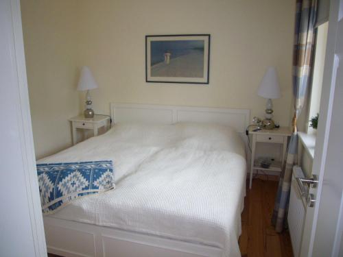 a bedroom with a white bed with two night tables at _BIR14_ Haus am Birkenweg in Niendorf