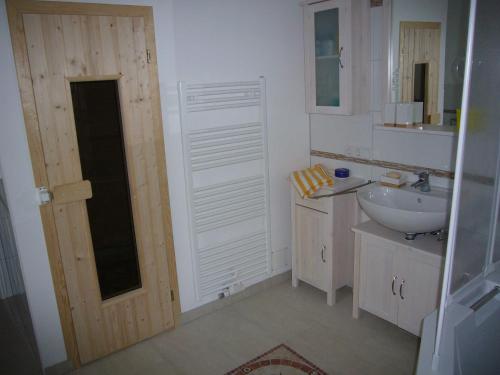 a bathroom with a sink and a toilet and a door at _BIR14_ Haus am Birkenweg in Niendorf