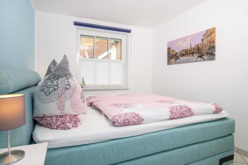 una cama con almohadas rosas y blancas encima en OST5a, en Niendorf