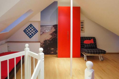 uma sala de estar com uma porta vermelha e uma cadeira em _OST6_ _ Ferienwohnung Treibholz em Niendorf