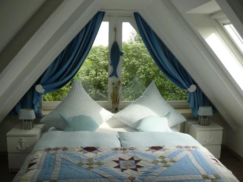 Schlafzimmer mit einem Bett mit blauen Vorhängen und einem Fenster in der Unterkunft (WIK7c) in Niendorf