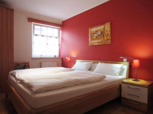 - une chambre avec un grand lit et un mur rouge dans l'établissement Ferienwohnung Ostseeblick, à Kühlungsborn