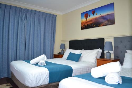 two beds in a hotel room with blue curtains at Lithgow Motor Inn in Lithgow