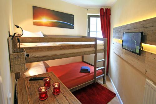 ブラウンラーゲにあるChalet Jägerstiegの二段ベッド2台とテーブルが備わる客室です。