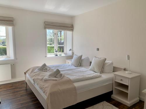 - une chambre blanche avec un lit et 2 fenêtres dans l'établissement Ferienwohnung 1 im Reetdachhaus Mühlenhof, à Sankt Peter-Ording